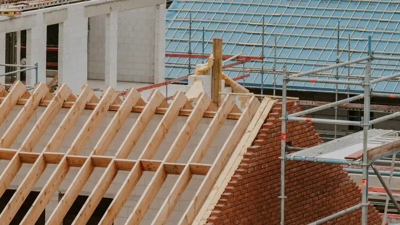 Neuer Dachstuhl aus Fichte auf einem Neubau aus Kalksandstein, mit Gerüst und Klinkergiebel