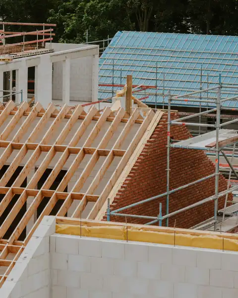 Neuer Dachstuhl aus Fichte auf einem Neubau aus Kalksandstein, mit Gerüst und Klinkergiebel