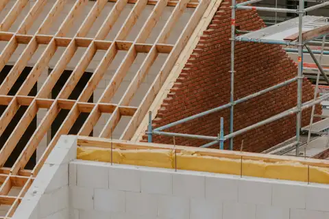 Neuer Dachstuhl aus Fichte auf einem Neubau aus Kalksandstein, mit Gerüst und Klinkergiebel