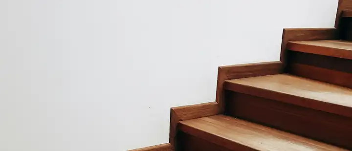 Gerade Holztreppe mit Massivholzstufen an einer weißen Wand
