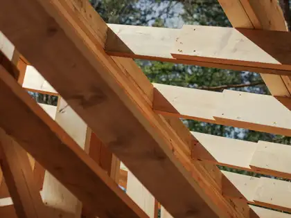 Sparren und Kehlbalken eines Holzhauses, von unten gegen den Himmel