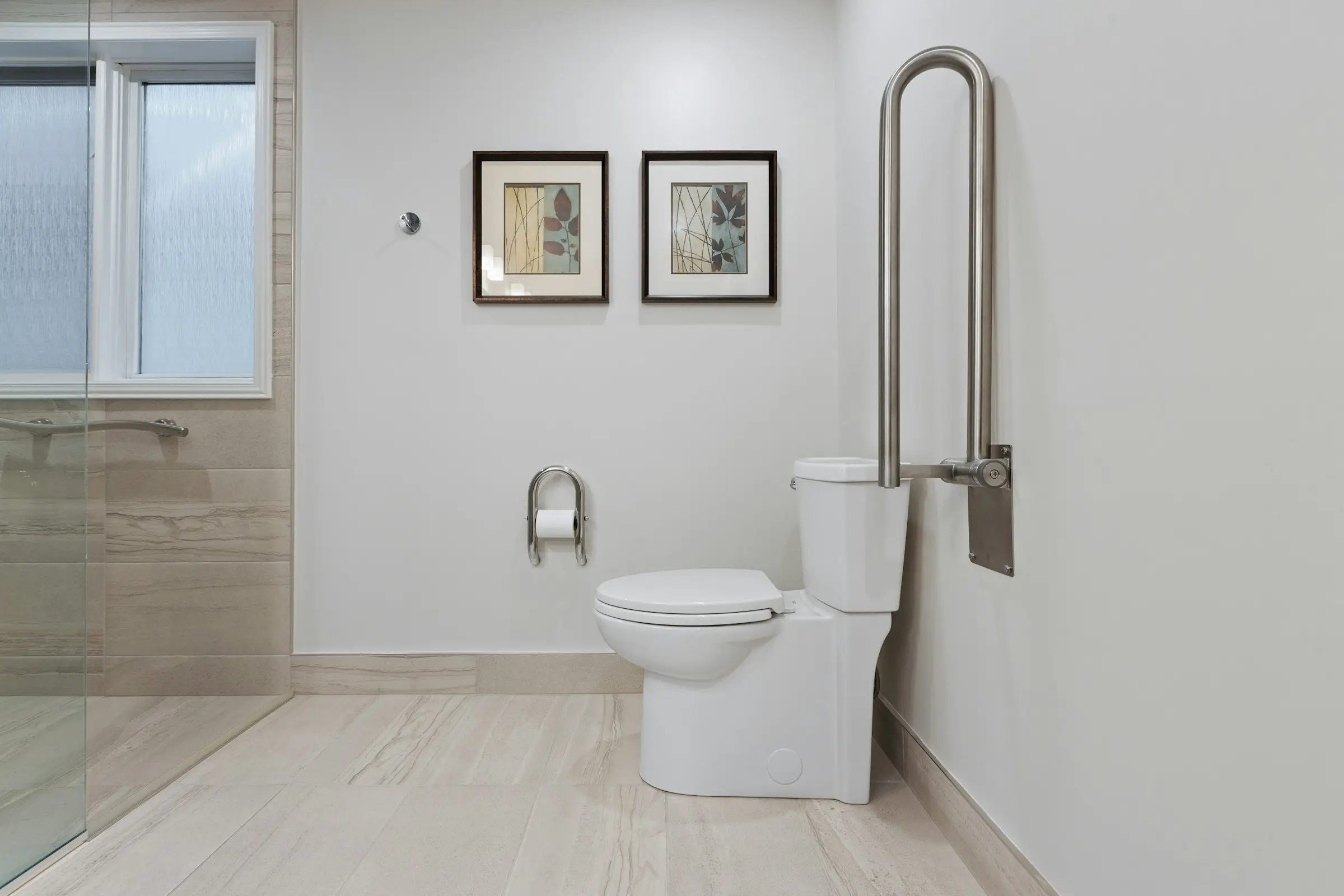 Helles Bad mit hochgeklapptem Stützgriff am WC und ebenerdiger Dusche mit Haltegriff