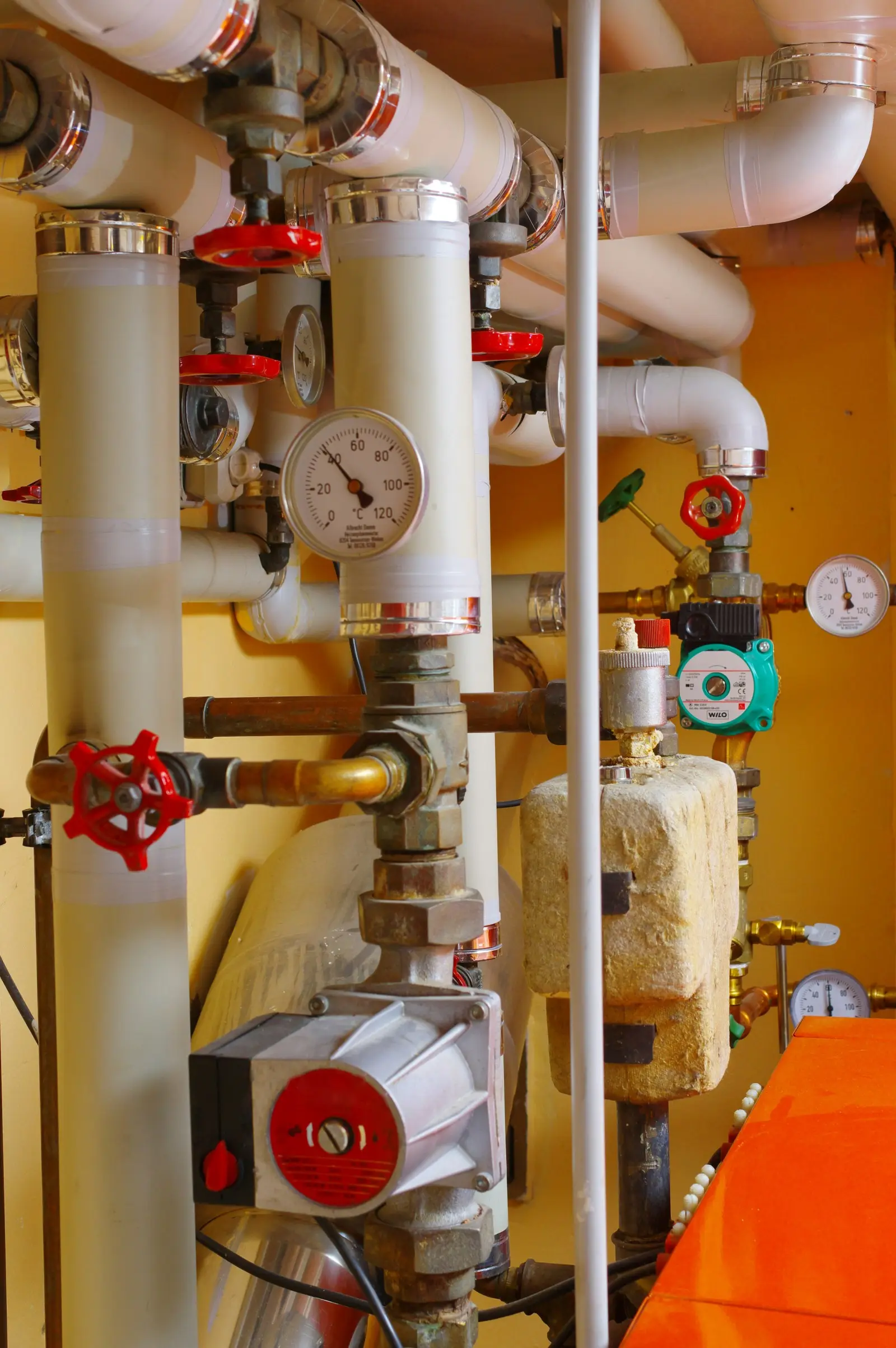 Heizungsrohre mit roten Absperrventilen, Pumpe und Thermometern