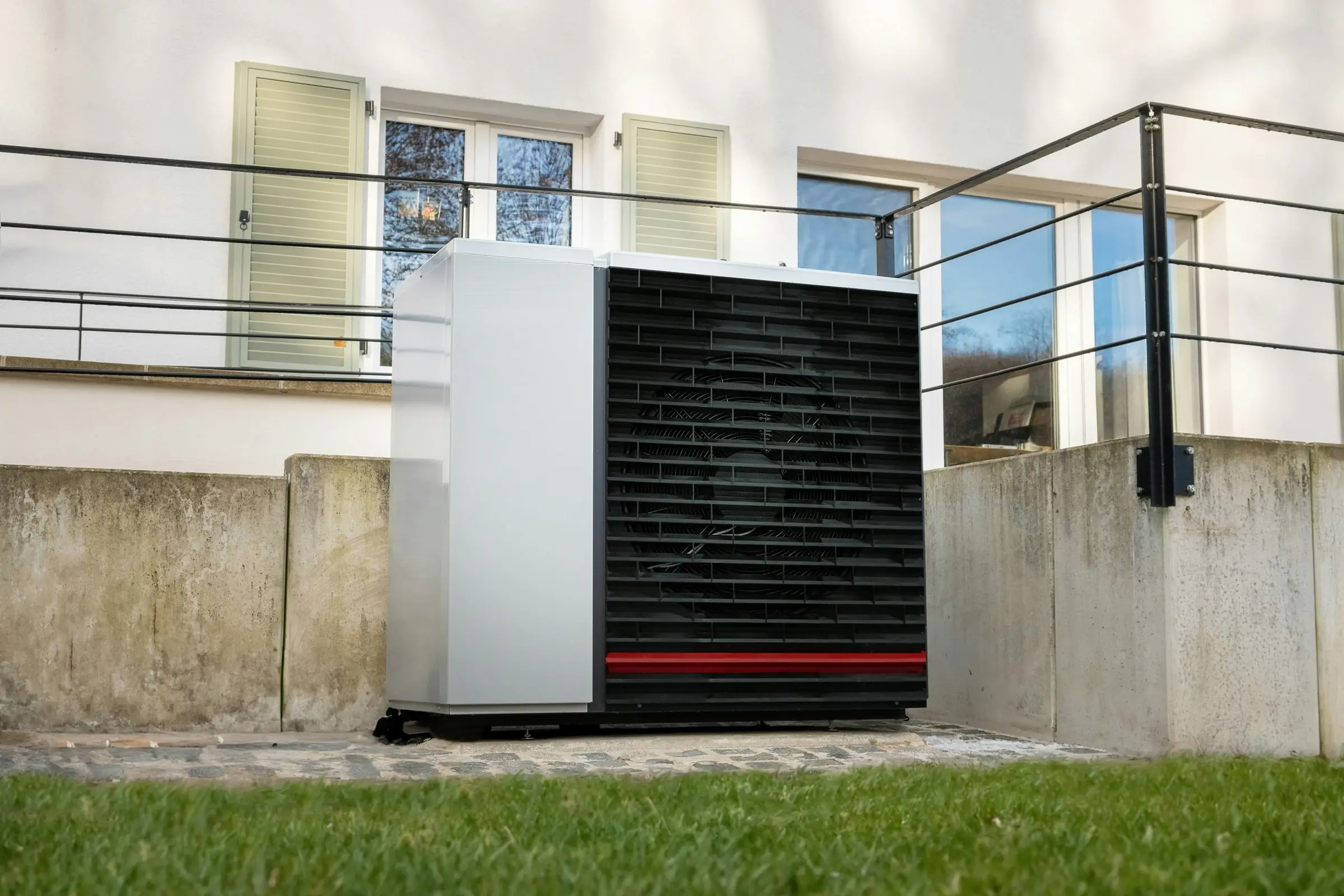 Wärmepumpe vor einem älteren Haus mit Fensterläden