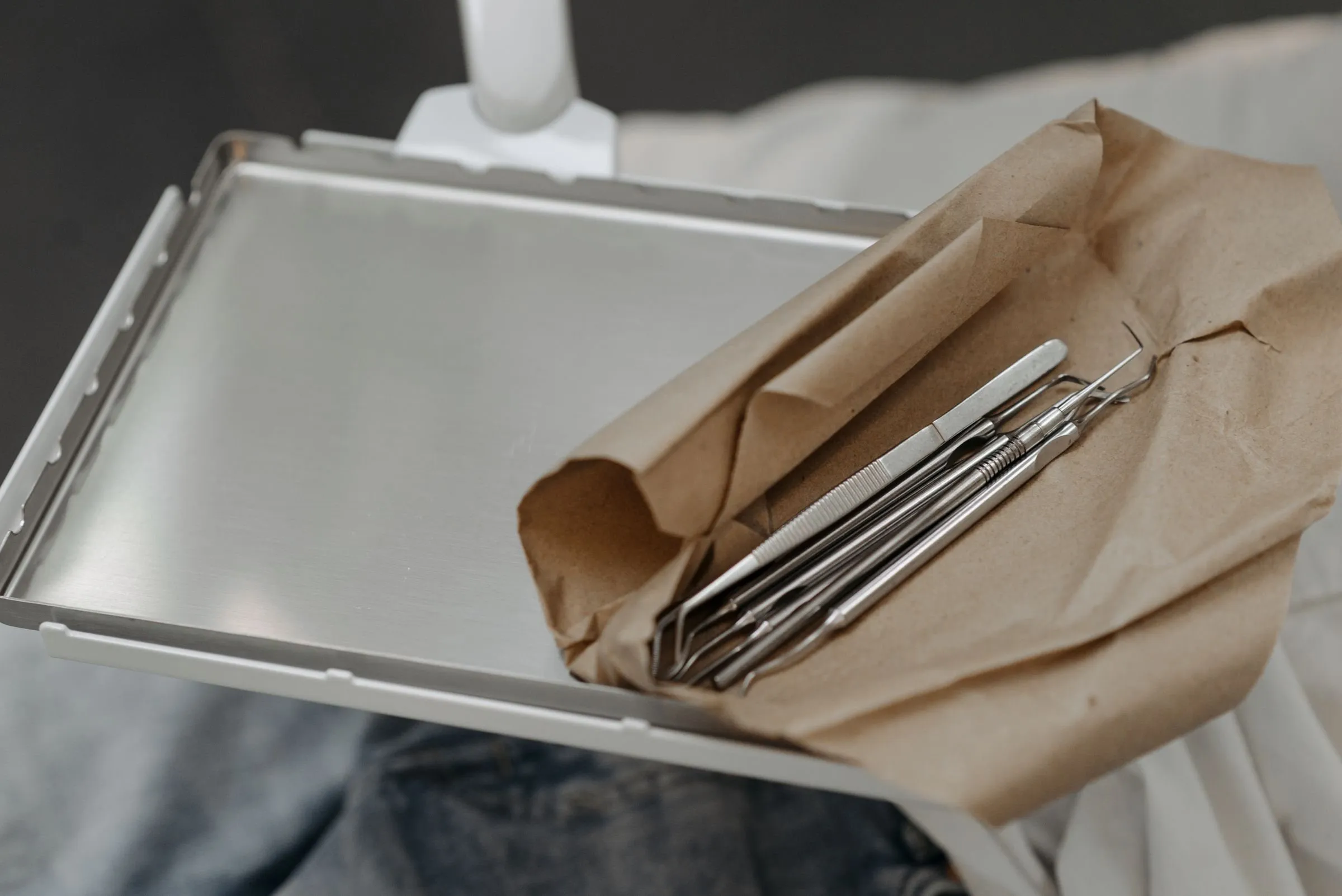 Tablett mit zahnärztlichen Instrumenten, halb in braunes Papier eingeschlagen